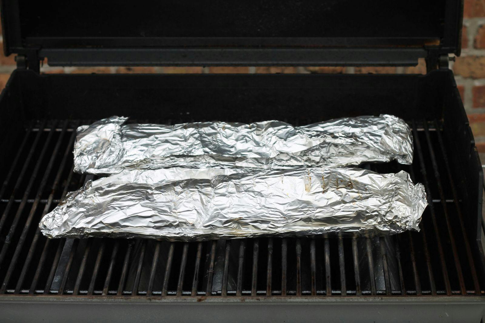 Packets of foil-wrapped ribs on the grill